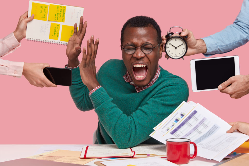 indoor shot of desperate young afro american man screams desperately, makes stop gesture, dressed in green sweater, busy working, isolated over pink background. people, work, depression concept