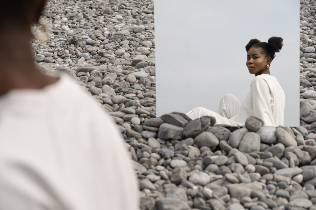 young woman dressed white posing with mirror rocks